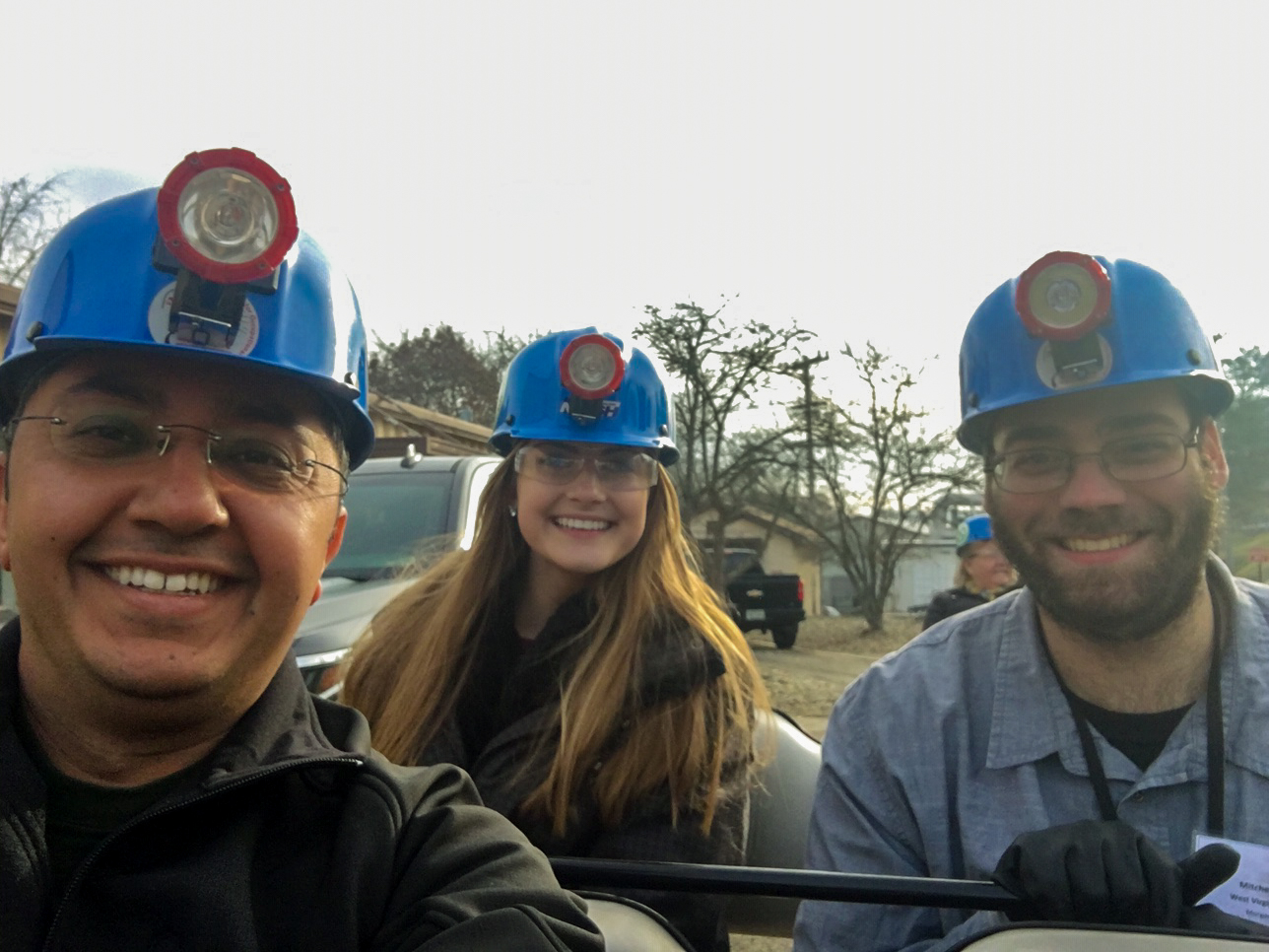 three people wearing safety helmets with lights